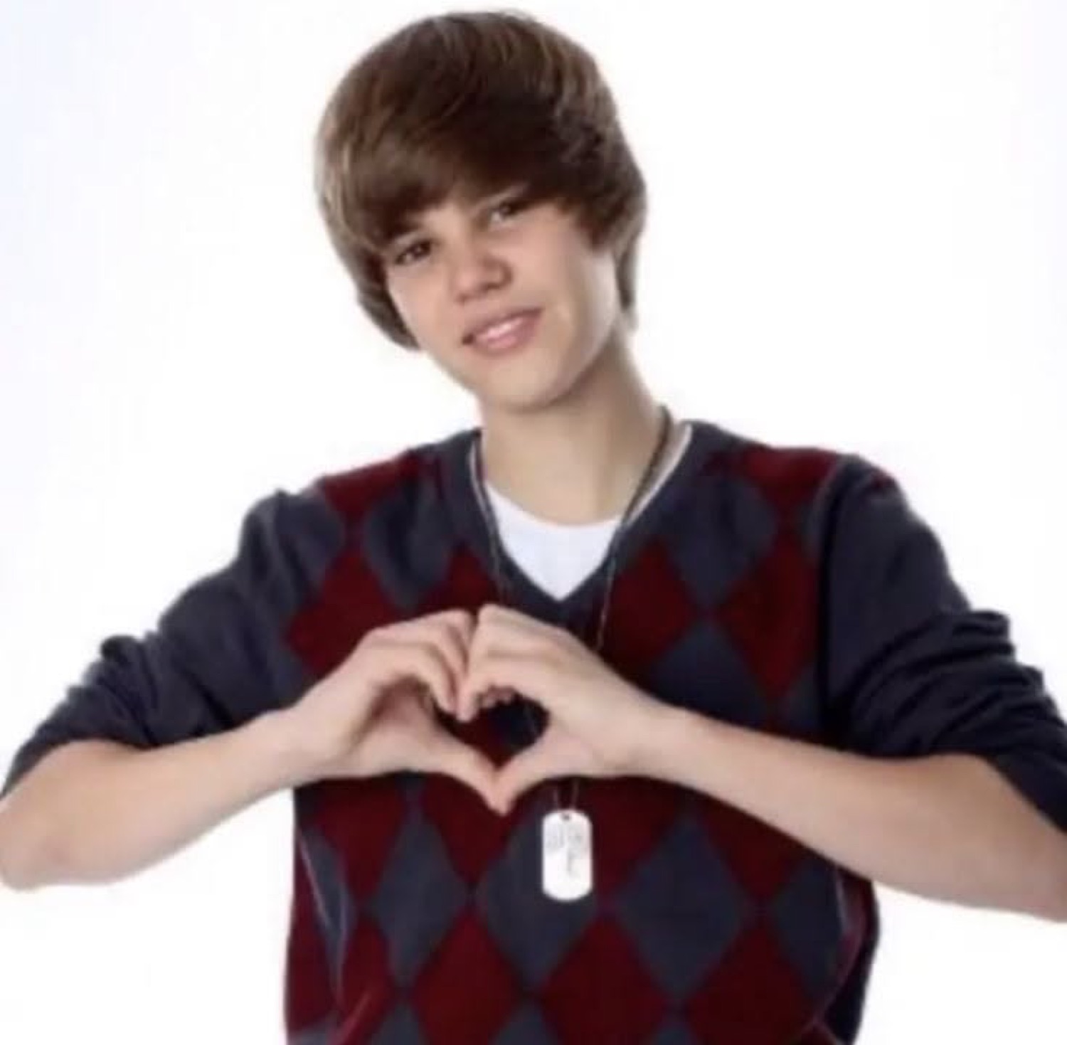 Young Justin Bieber smiling and making a heart shape with his hands