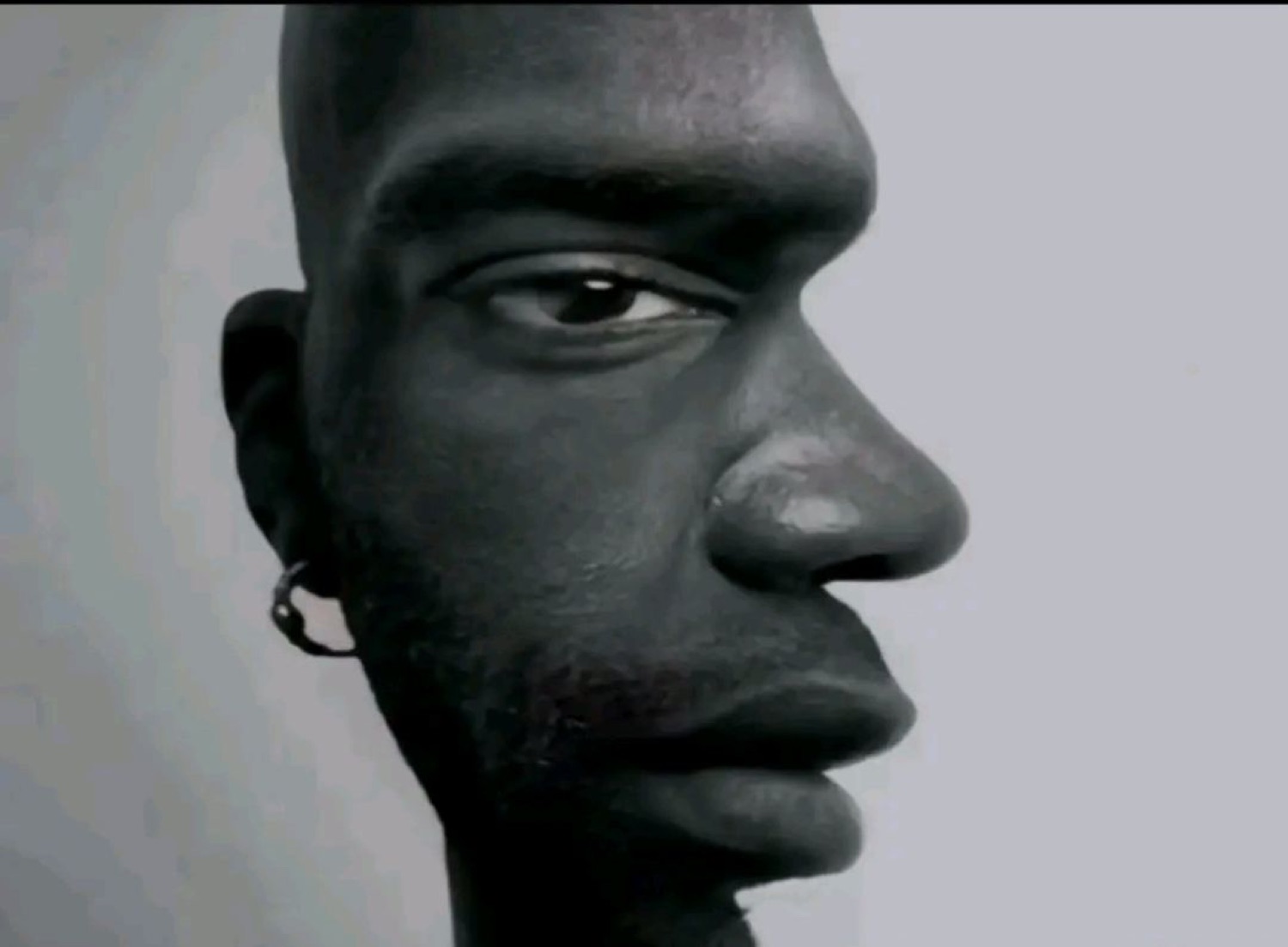 Black and white close-up of a man's face in profile with a flat, unreadable stare