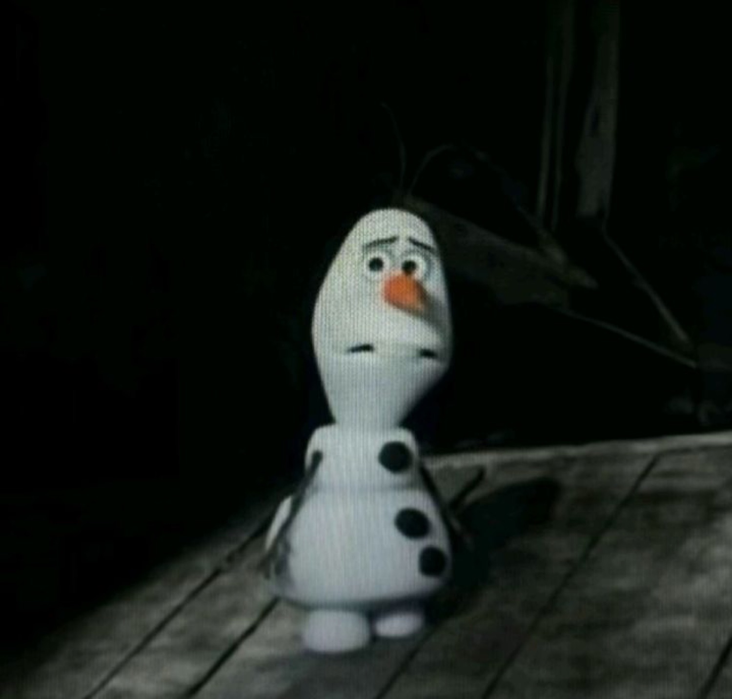 A deflated sock-puppet Olaf standing alone in the dark looking sad and small