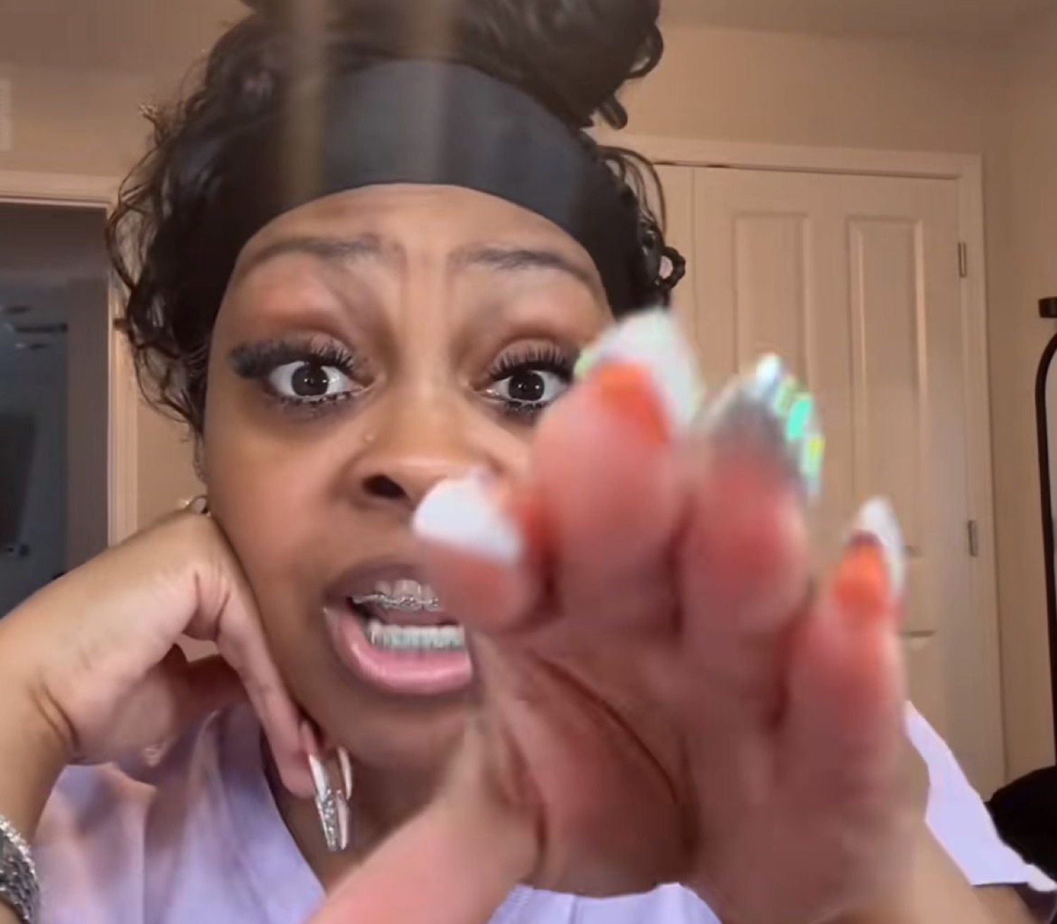 Woman with bedazzled nails pointing at the camera with an intense, wide-eyed accusatory look