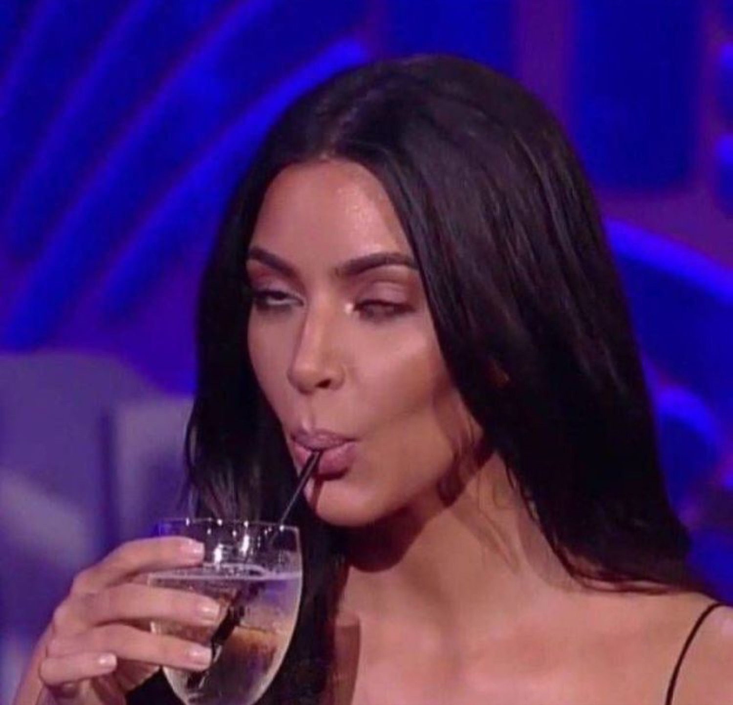 Kim Kardashian sipping a drink through a straw while side-eyeing off camera