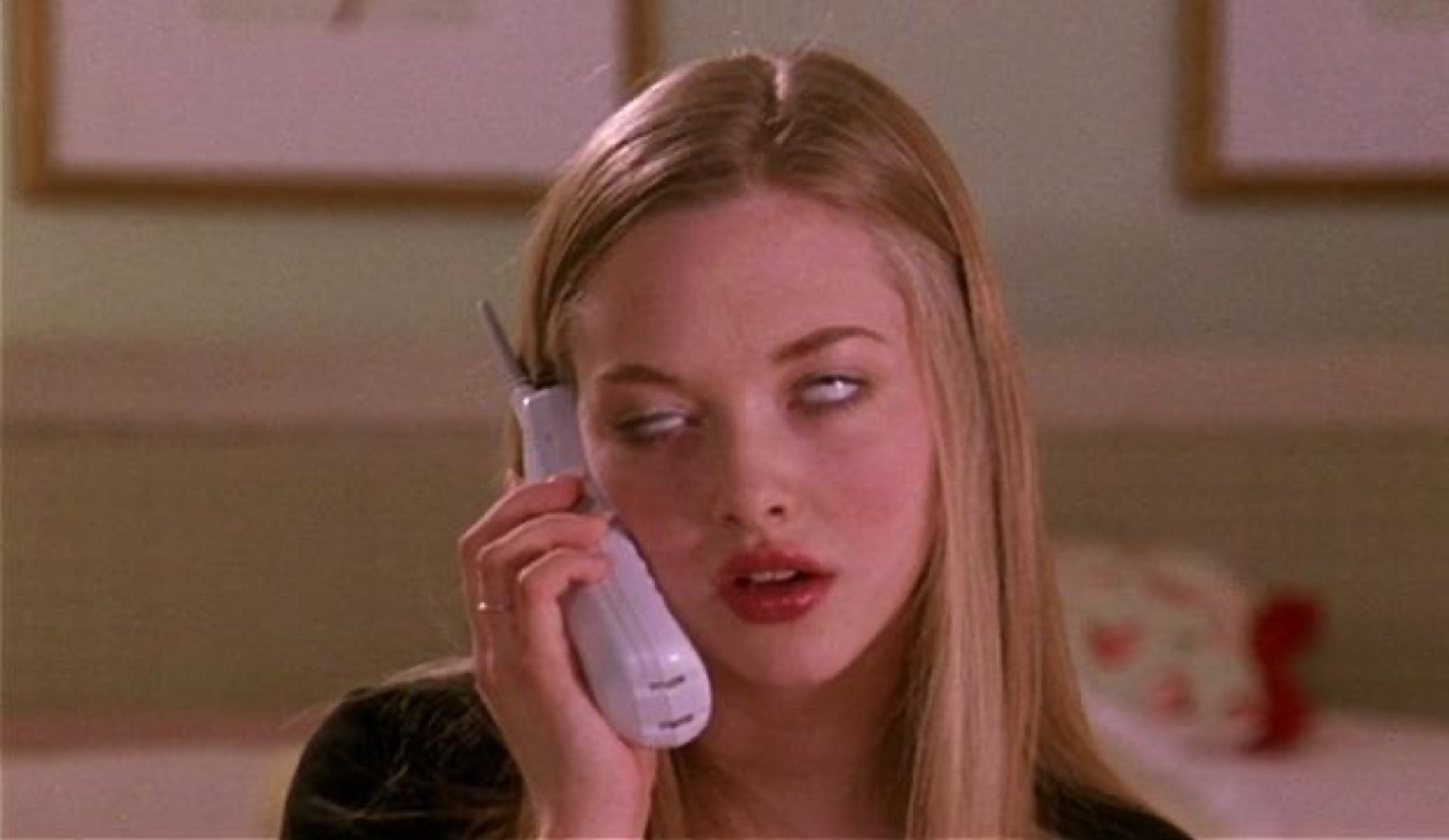 Blonde girl on a cordless phone rolling her eyes with a bored, unbothered look