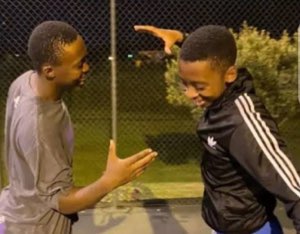 Two grinning boys about to high-five each other on a nighttime court