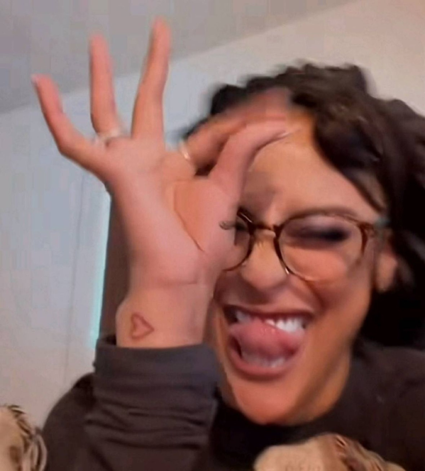 Woman with glasses cracking up and making a goofy face at the camera
