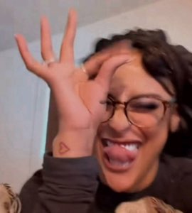 Woman with glasses cracking up and making a goofy face at the camera