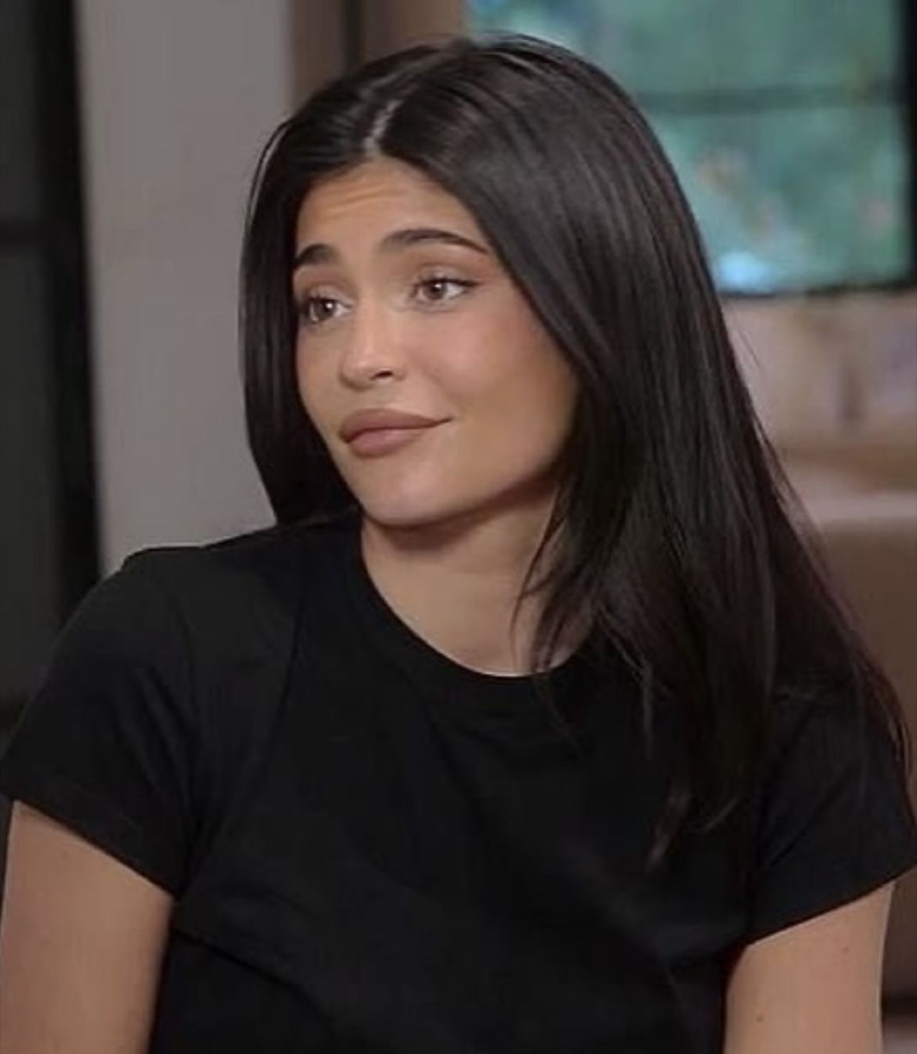 Woman in a black tee giving a subtle unimpressed smirk during an interview