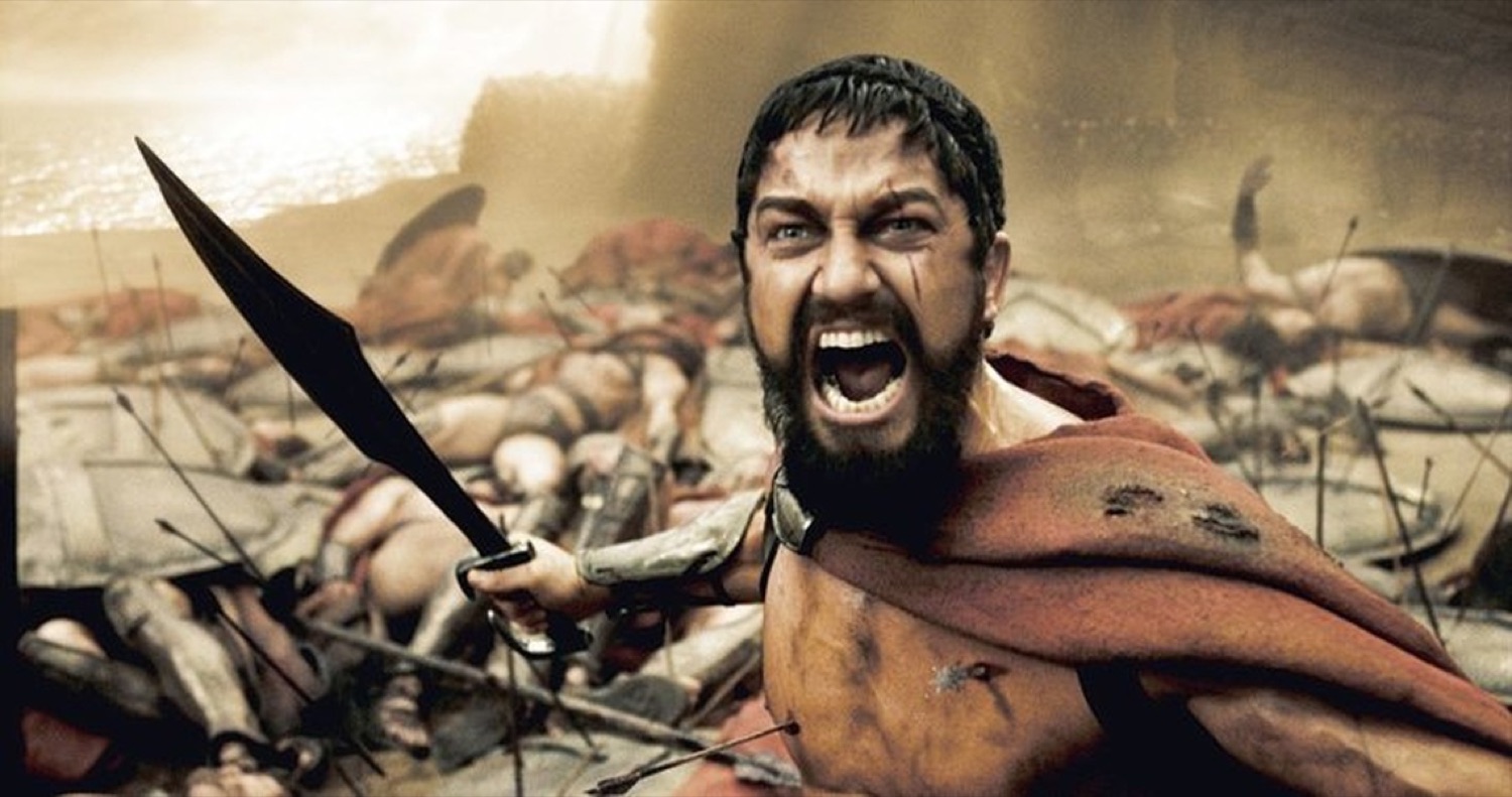 Bearded Spartan warrior raising his sword and roaring in the middle of battle