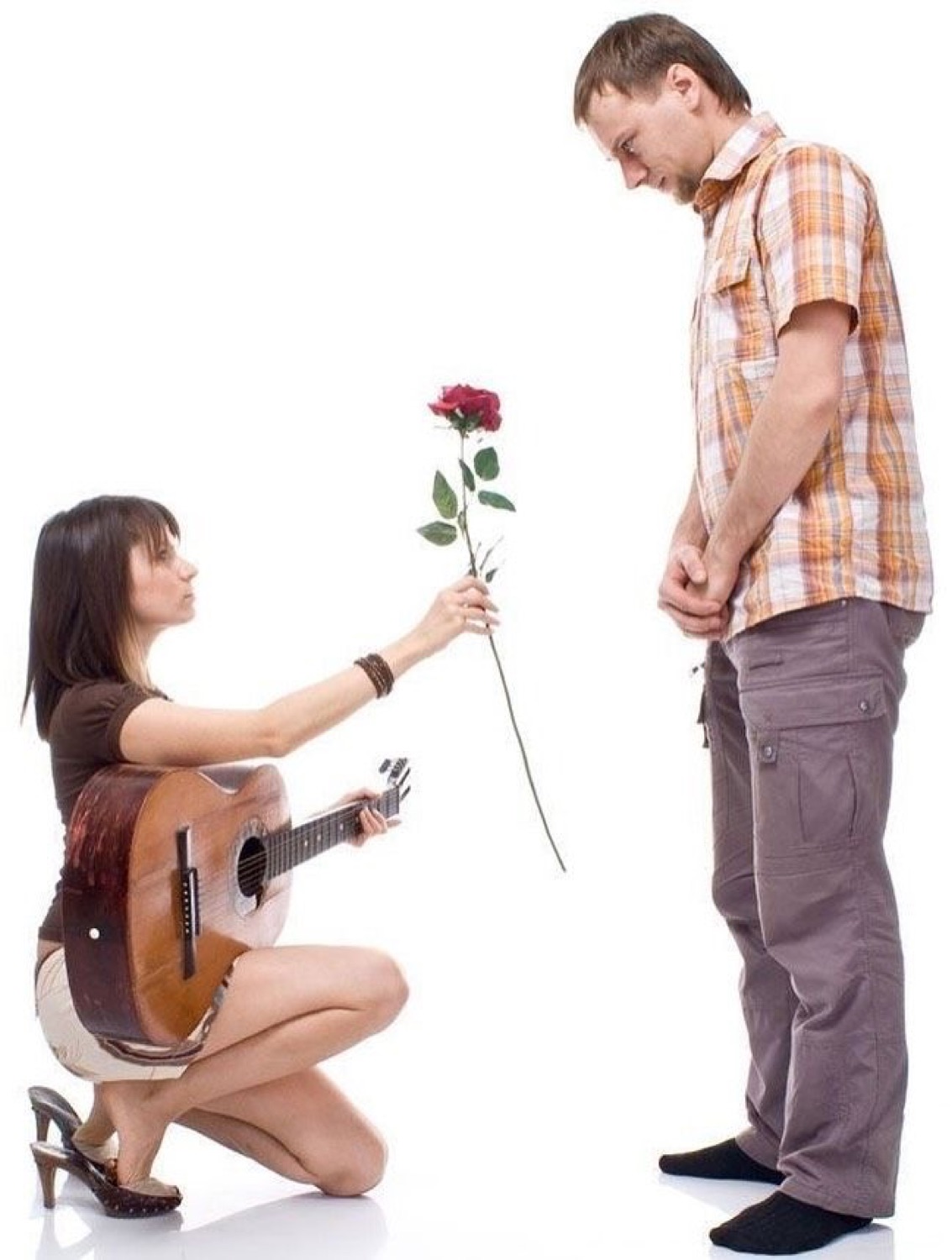 Woman kneeling with a guitar offering a rose to a man who stares down unimpressed