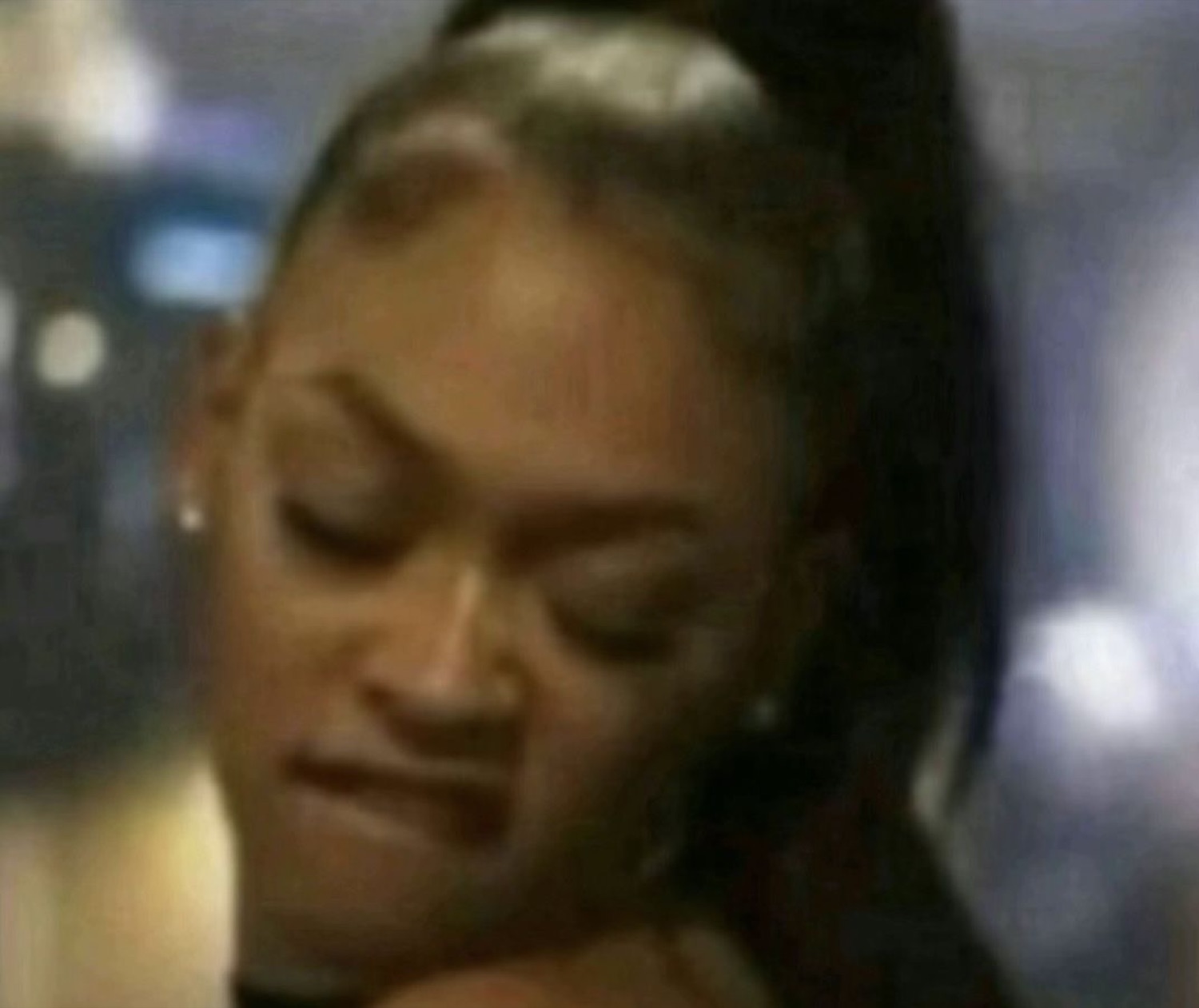 Woman with a high ponytail looking down with a smug, unbothered smirk