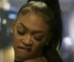 Woman with a high ponytail looking down with a smug, unbothered smirk