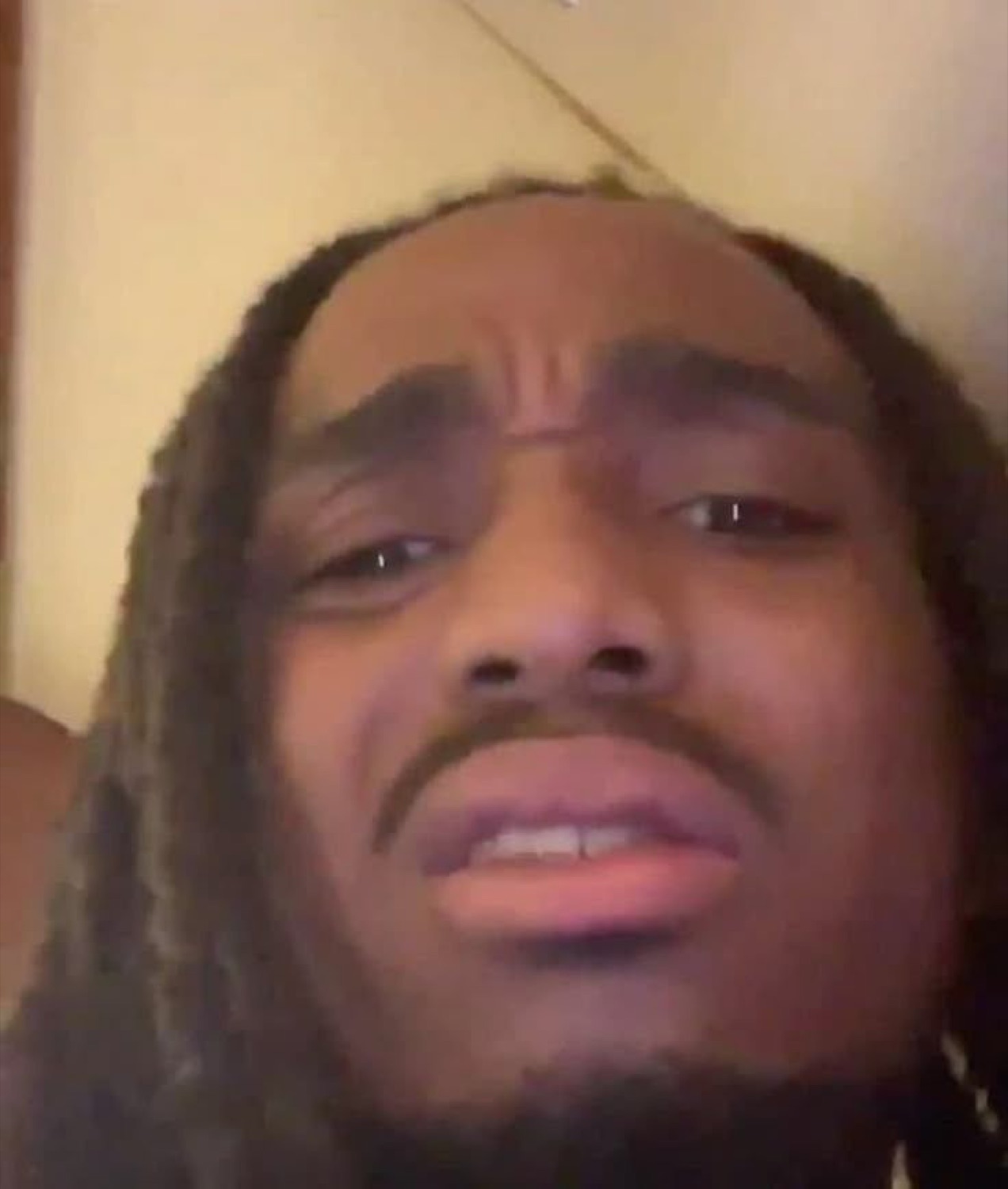 Guy with locs looking up with heavy-lidded eyes and a deeply unimpressed expression