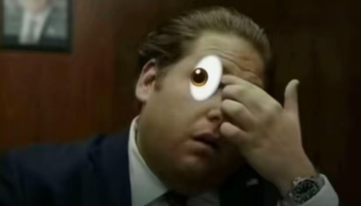 Man holding a cartoon googly eye over his own eye, staring in wide-eyed disbelief