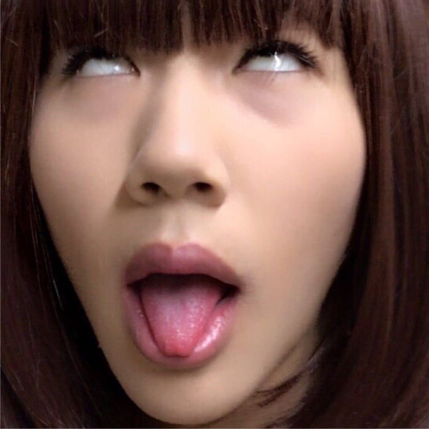 Woman with bangs rolling her eyes back with mouth open and tongue out