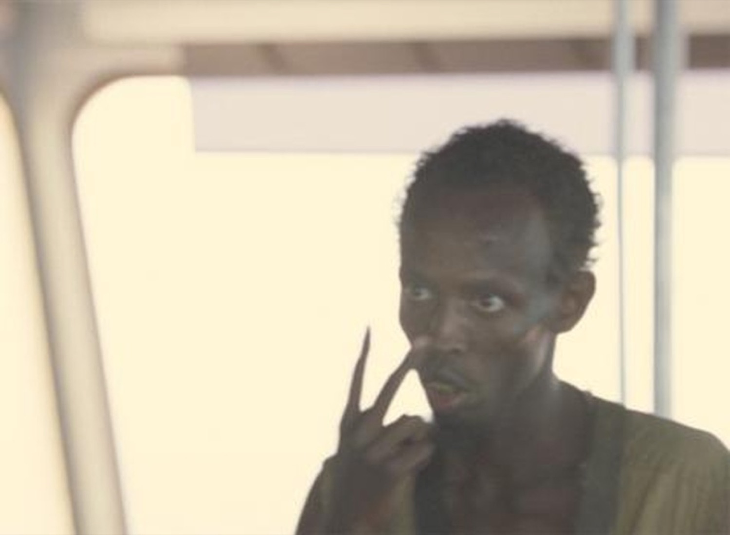 Man on a boat pointing to his nose and eye with a sly knowing look
