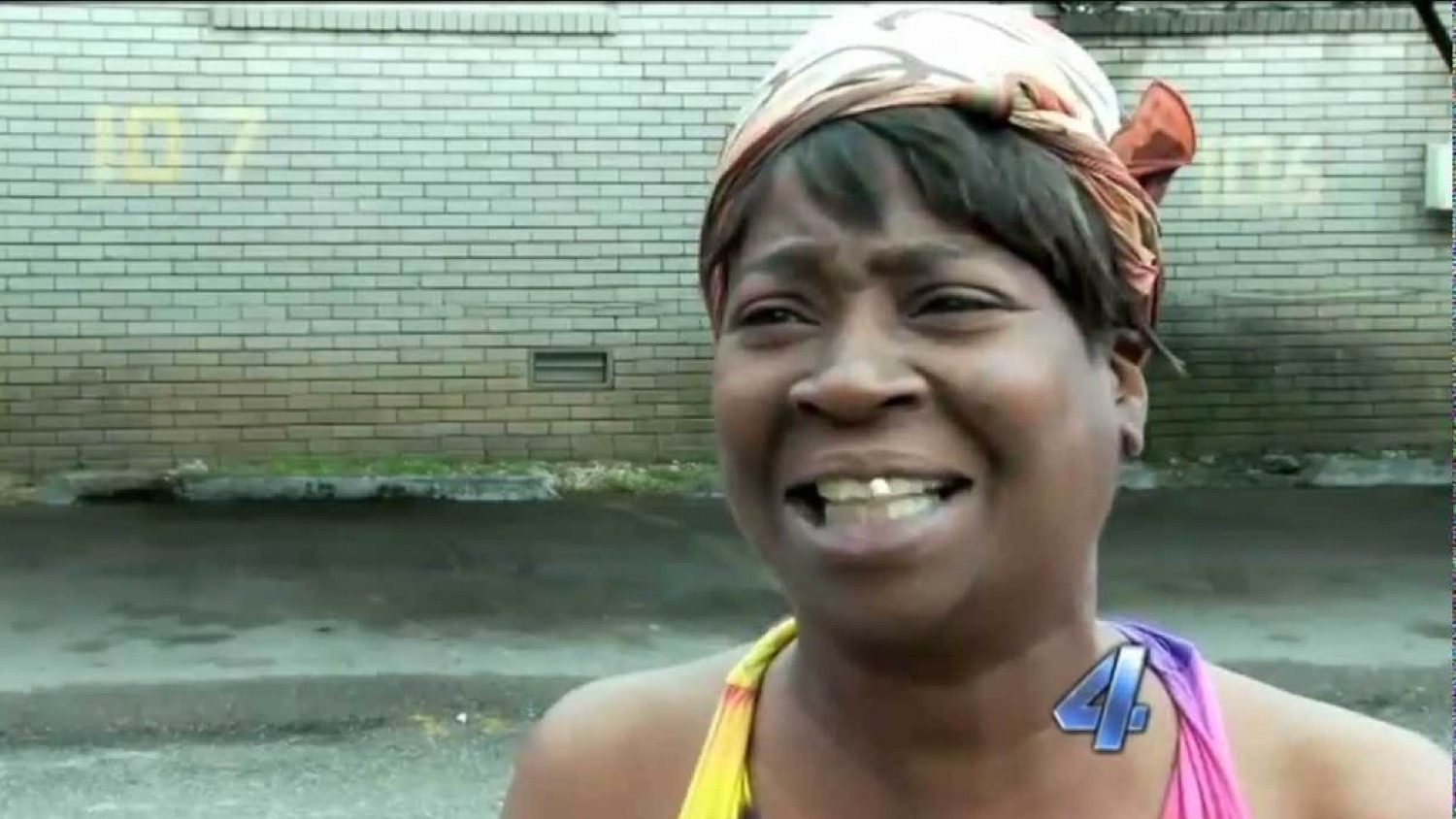 Woman in a headscarf on the news squinting with an ain't-nobody-got-time expression