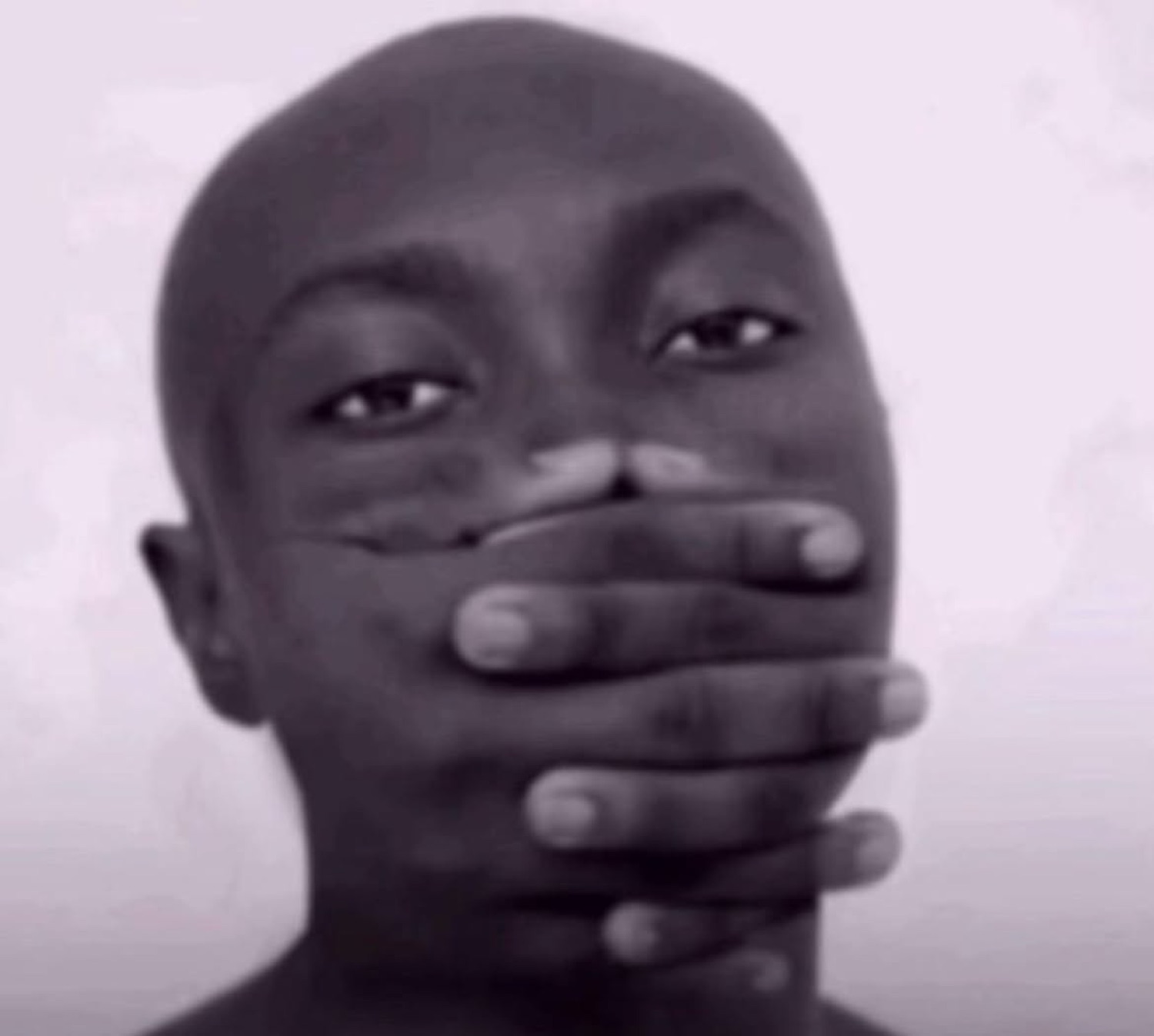 Person covering their mouth with both hands in a grainy black-and-white close-up, laughing and shocked