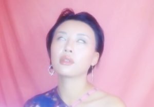 Woman against a pink backdrop rolling her eyes back dramatically mid-sigh
