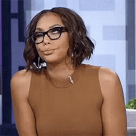 Woman in glasses smirking and cutting a skeptical side-eye off camera