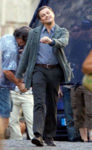 Leonardo DiCaprio laughing and pointing forward while strolling on set