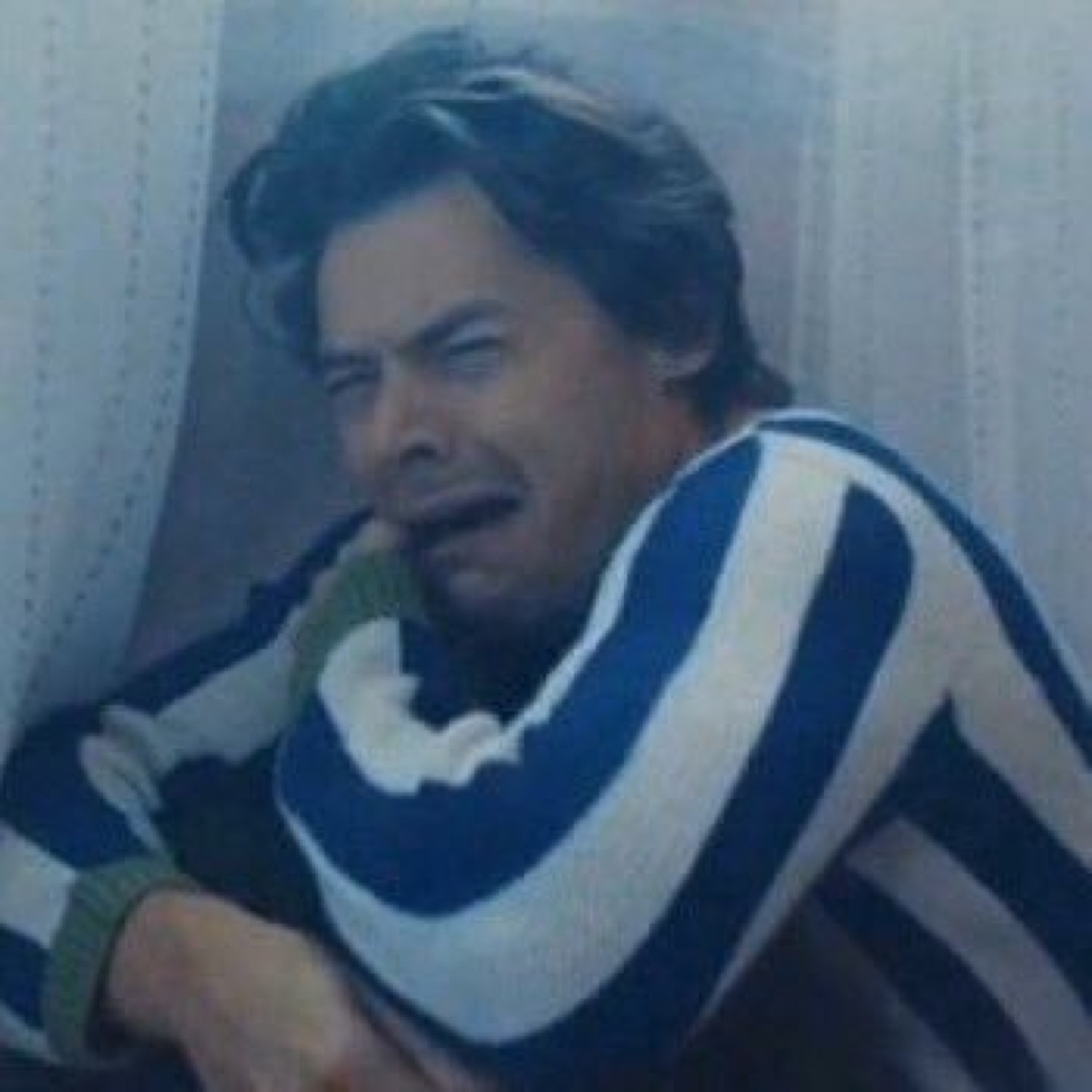 Harry Styles in a striped sweater weeping against a wall, fully giving in to the feeling