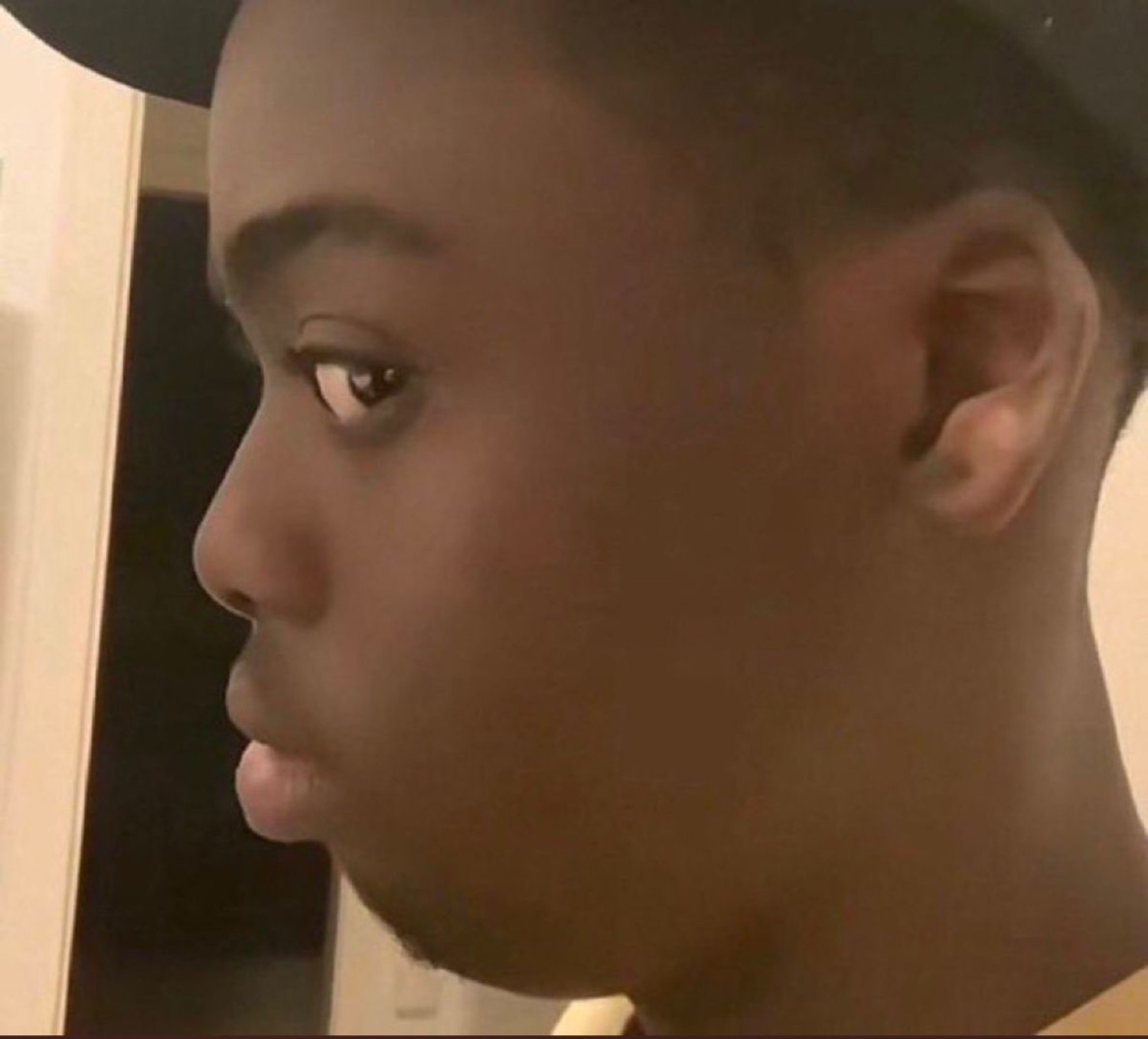 Young man in profile cutting a wary, suspicious side-eye at the camera