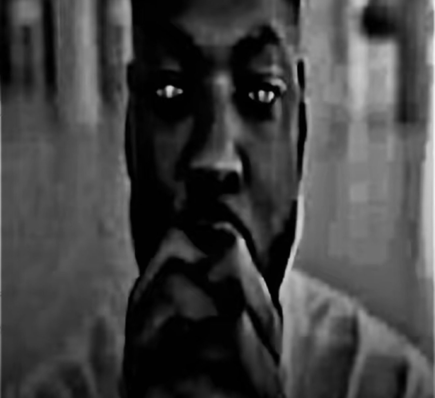 Grainy black-and-white shot of a man staring intensely, eyes catching the light