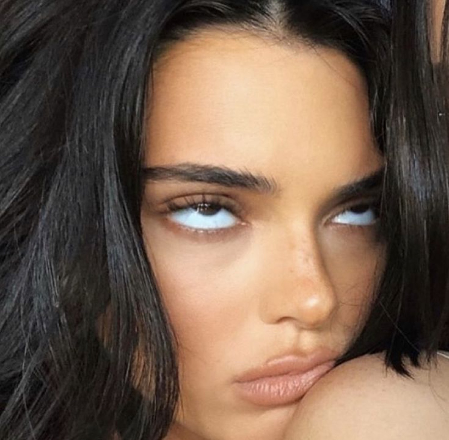 Dark-haired woman with icy side-eye stare, resting her chin on her arm looking completely over it