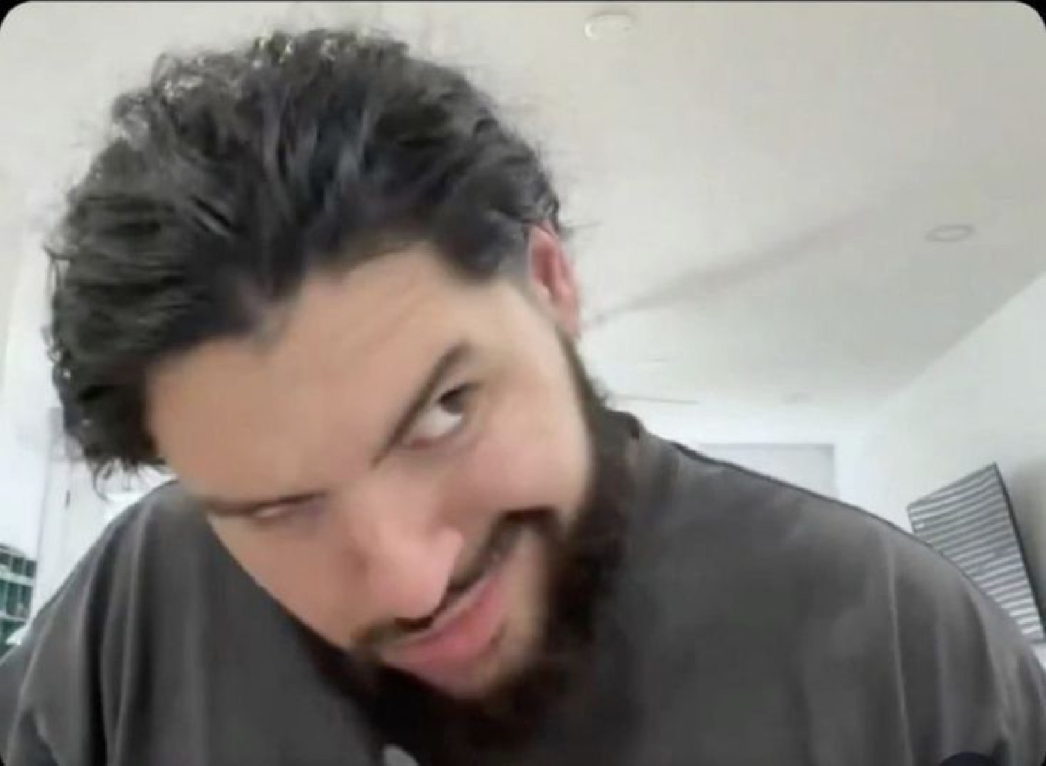 Bearded guy leaning into the webcam with a sly suspicious grin