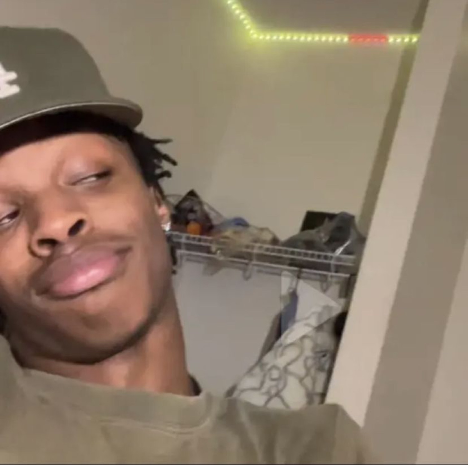 Guy in a cap taking a low-angle selfie with a smug, unbothered smirk