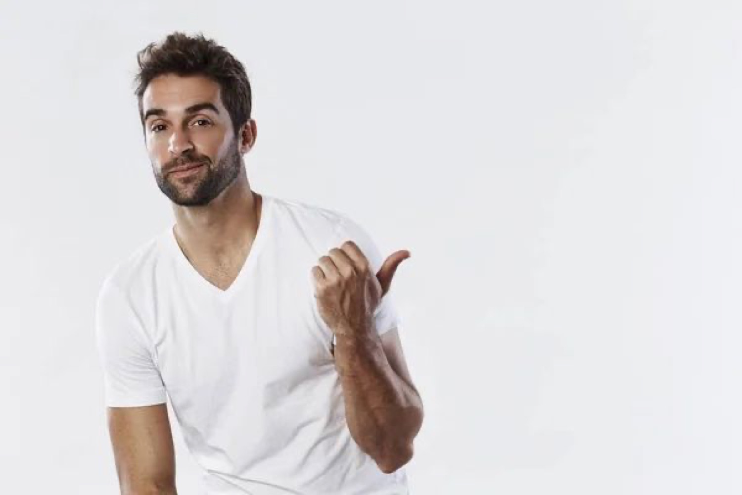 Man in a white tee smirking and jerking his thumb over to the side