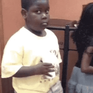 Young boy in a yellow shirt cutting a wary side-eye at someone off to the side