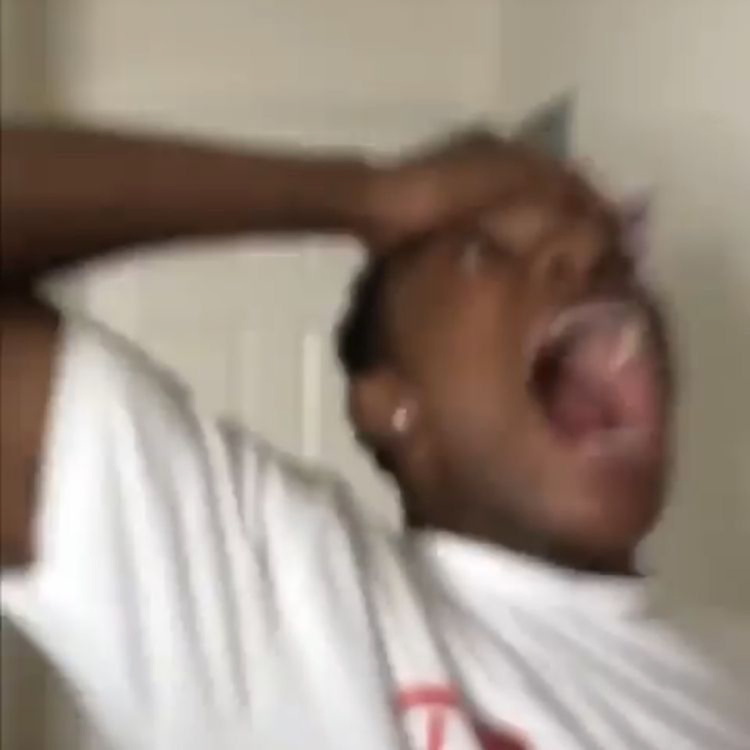 Man in a white shirt clutching his head and screaming his lungs out