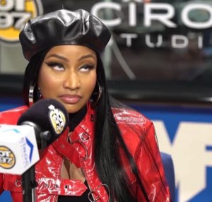 Nicki Minaj in a red jacket and beret rolling her eyes hard during an interview