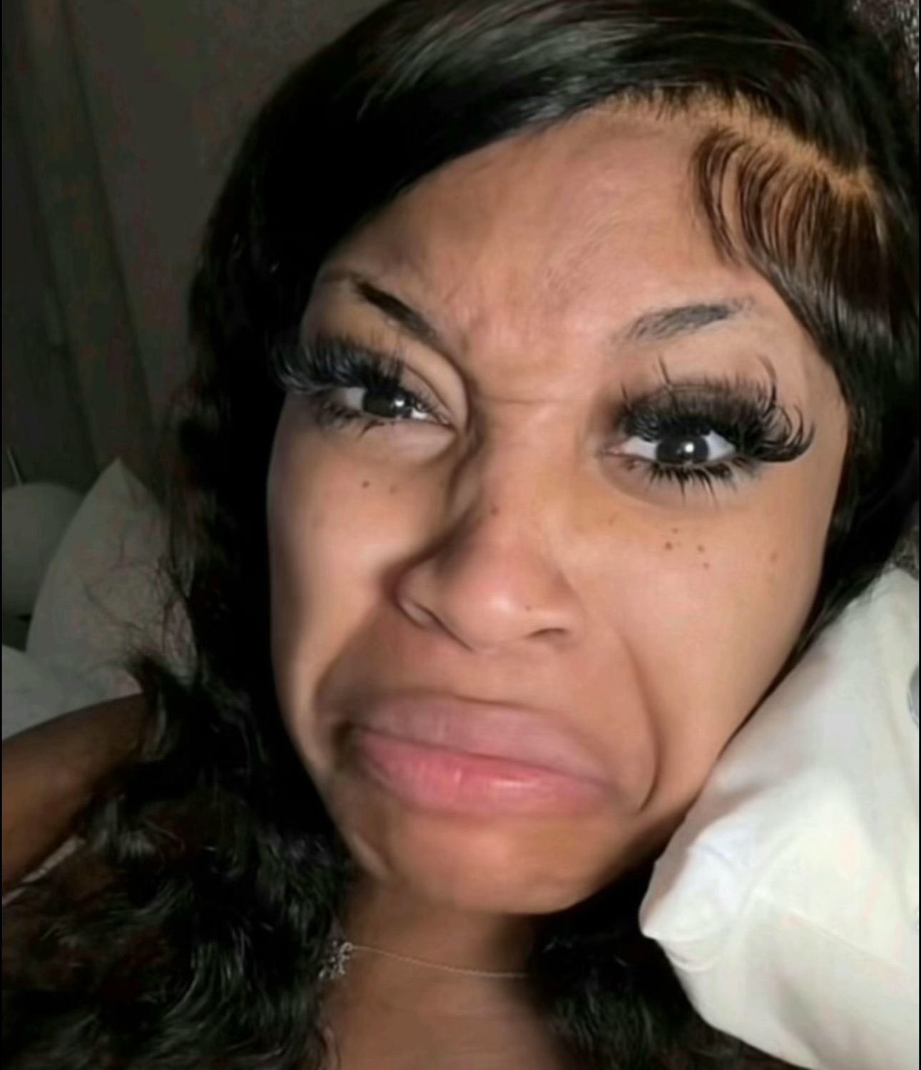 Woman lying down scrunching her face into an intense disgusted grimace
