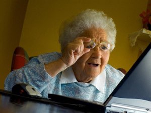 Grandma squinting through her glasses at a laptop, baffled by the screen
