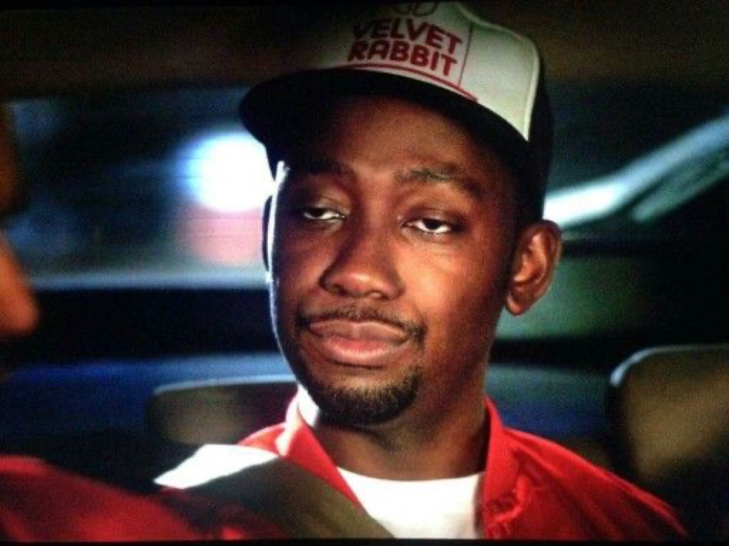 Guy in a 'Velvet Rabbit' trucker hat giving a smug, satisfied smirk in a car