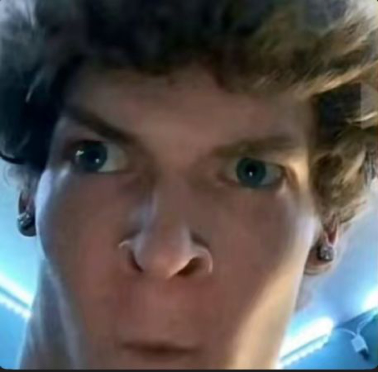 Young man leaning close to the camera with an intense, suspicious glare