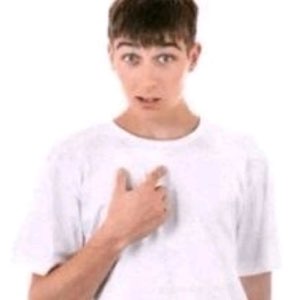 Teen in a white shirt looking flustered and awkward, hand on his chest