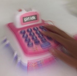 Toy pink cash register with 'girl idk' on the display and a hand hitting the keys