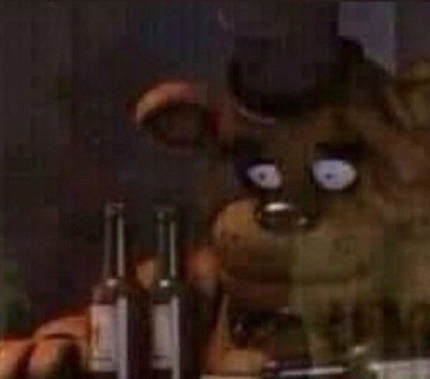 Animatronic bear lurking in the dark with beady glowing eyes behind some bottles