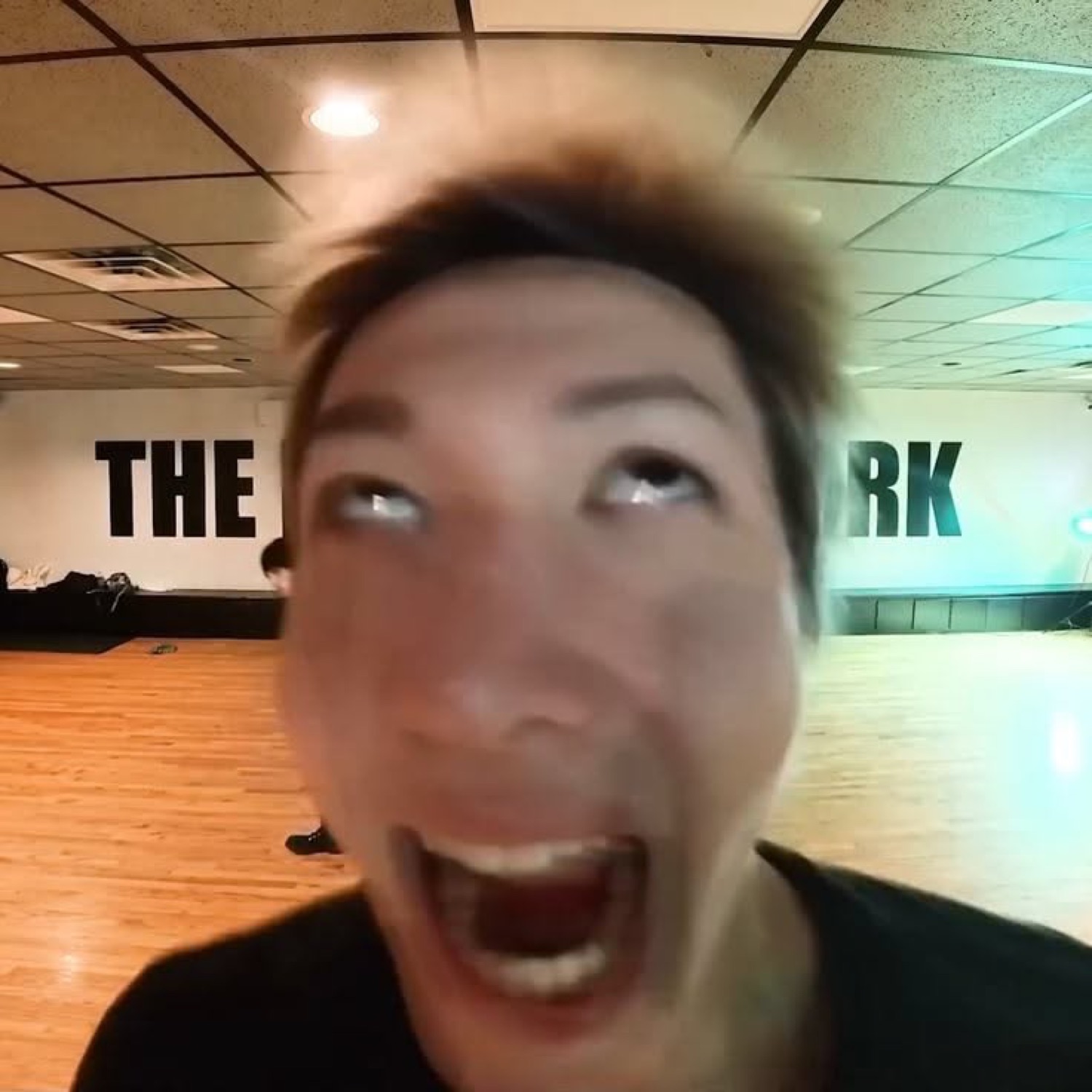 Man in a dance studio laughing maniacally with rolling eyes at the camera