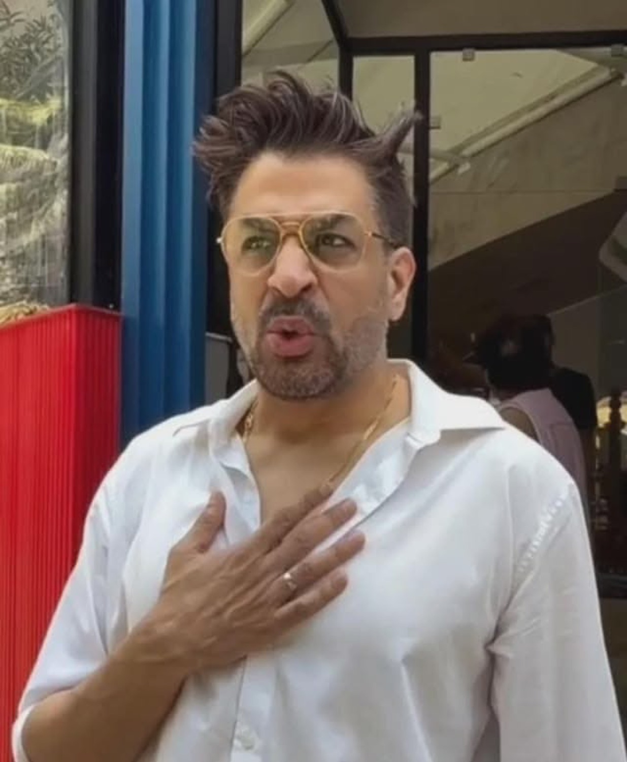 Man in tinted glasses with a hand on his chest, offended and shocked