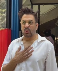 Man in tinted glasses with a hand on his chest, offended and shocked