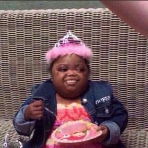 Woman in a pink tiara grinning while digging into a slice of birthday cake