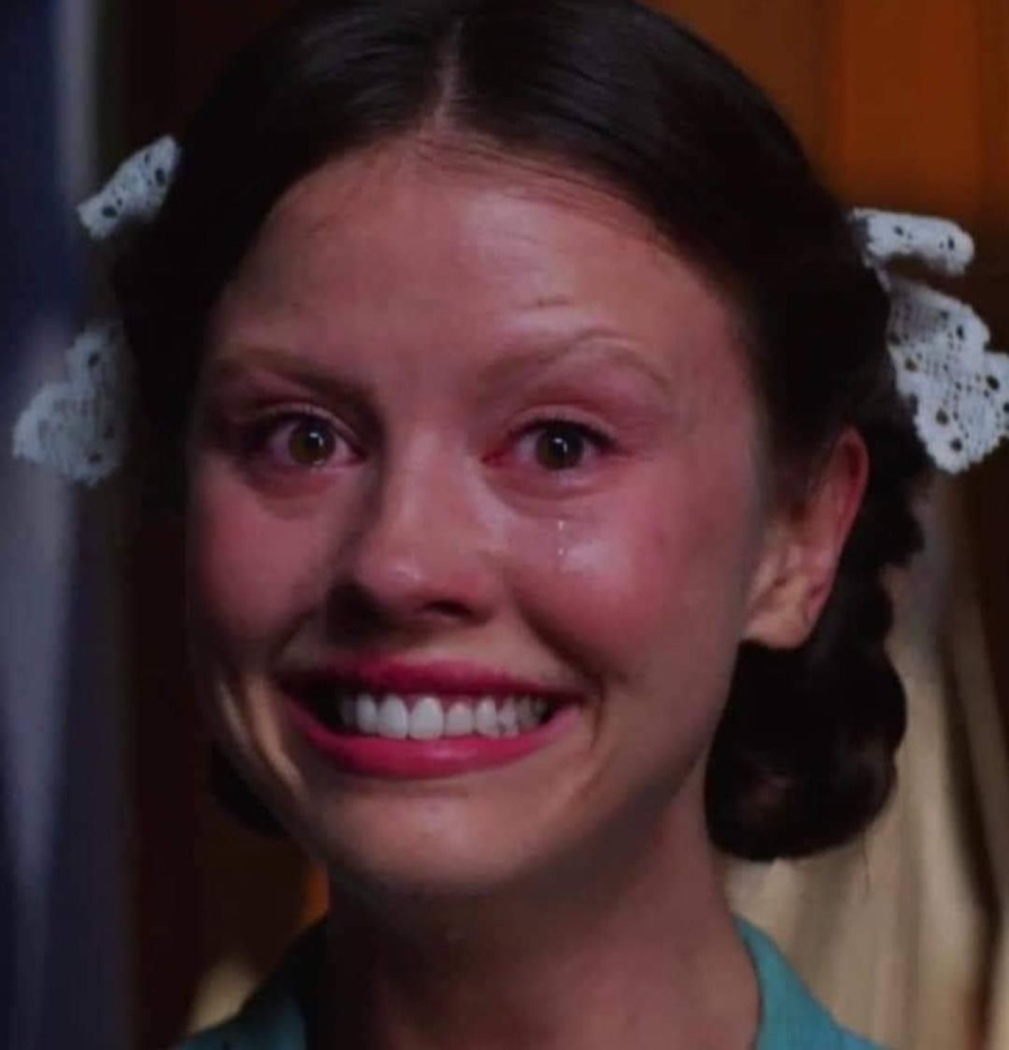 Mia Goth as Pearl with a teary, unhinged forced smile