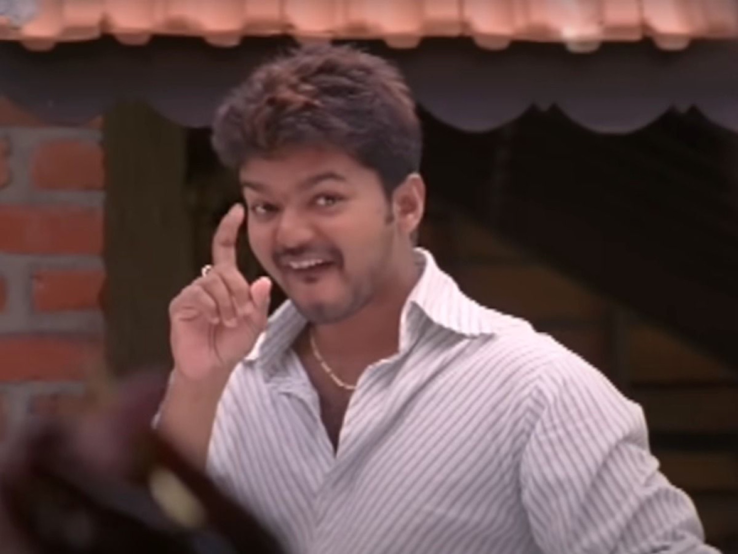 Vijay grinning and tapping his temple
