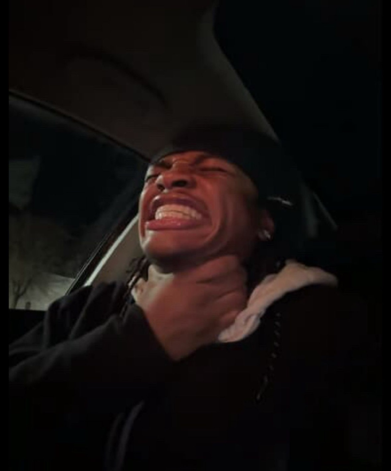Guy in the backseat of a car throwing his head back laughing uncontrollably