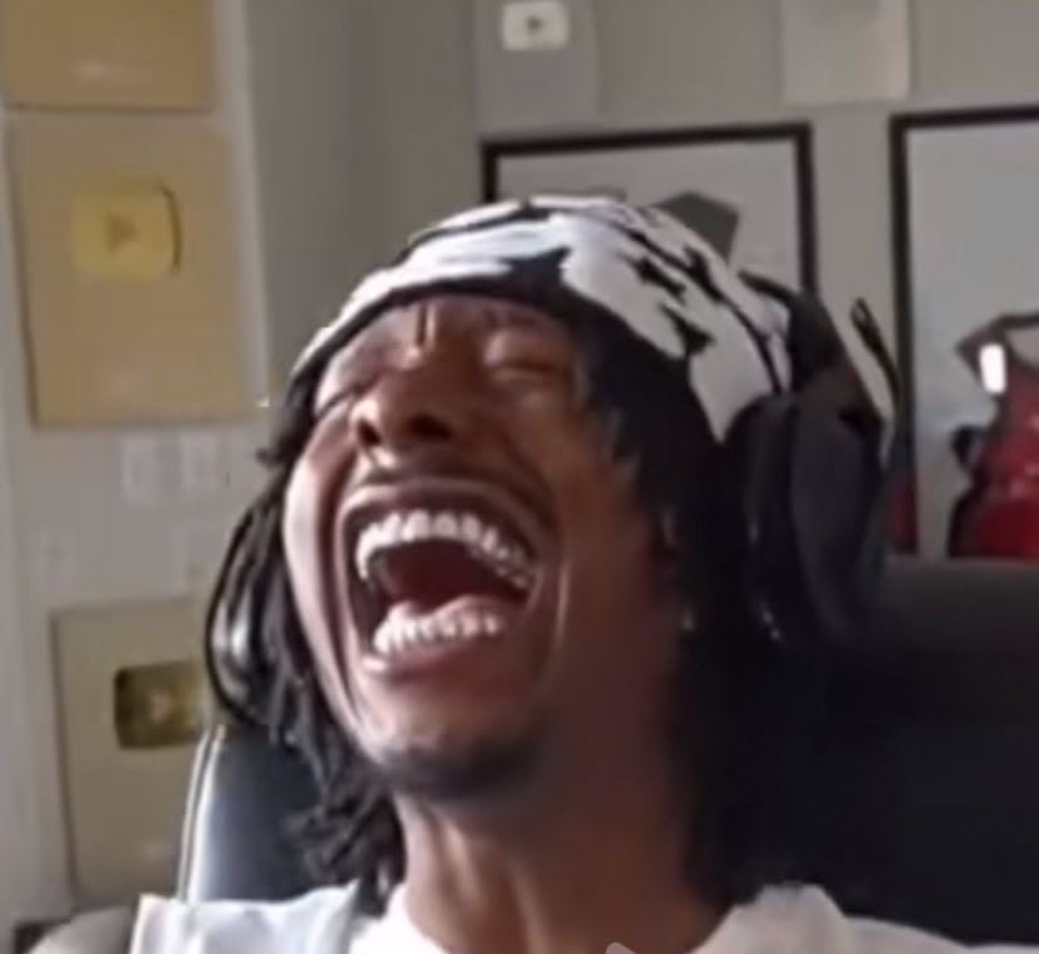 Man in a headscarf and headphones cracking up laughing with his head thrown back