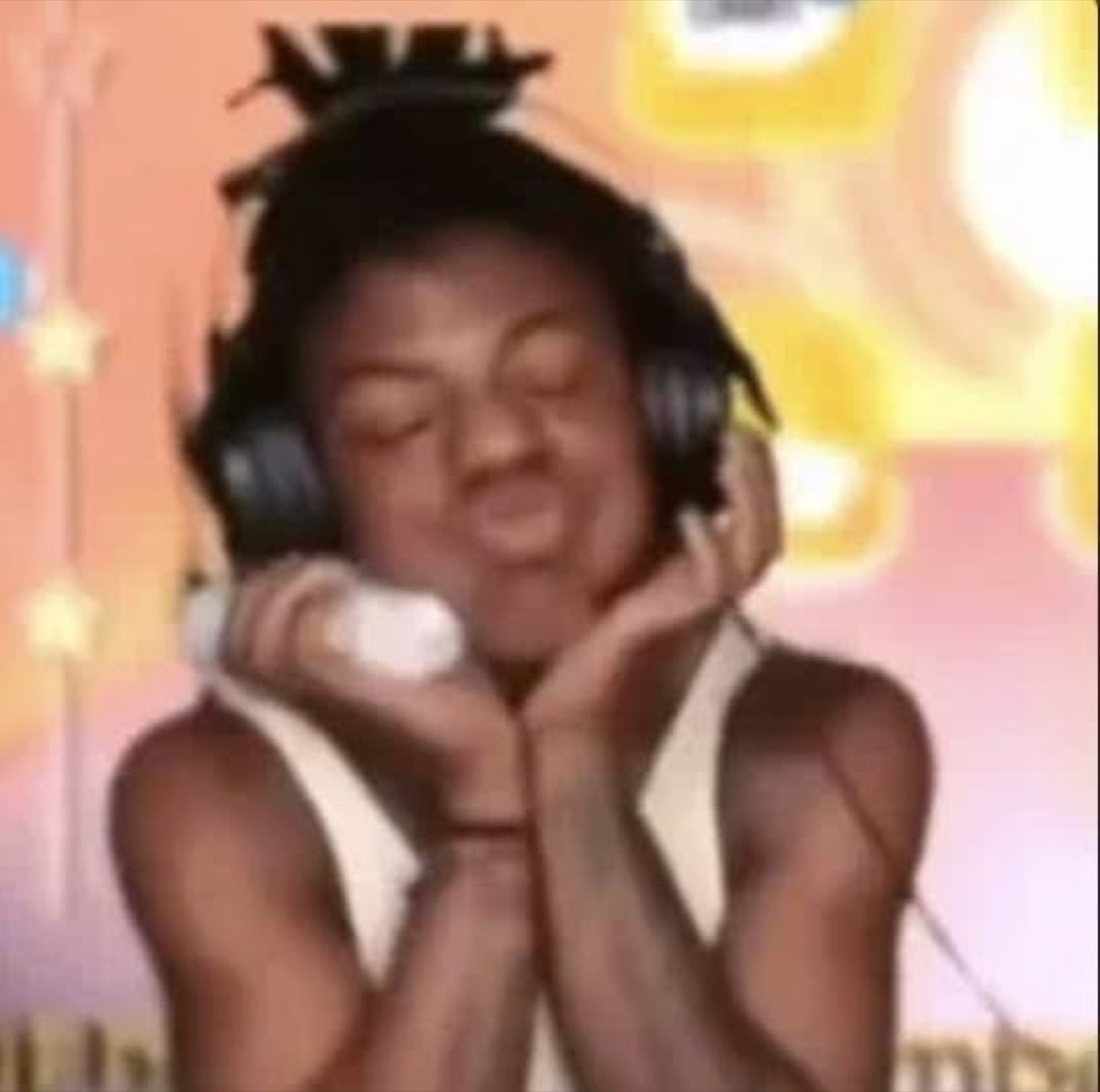 Young person with headphones on, eyes closed and head tilted in blissful contentment, cradling the headset