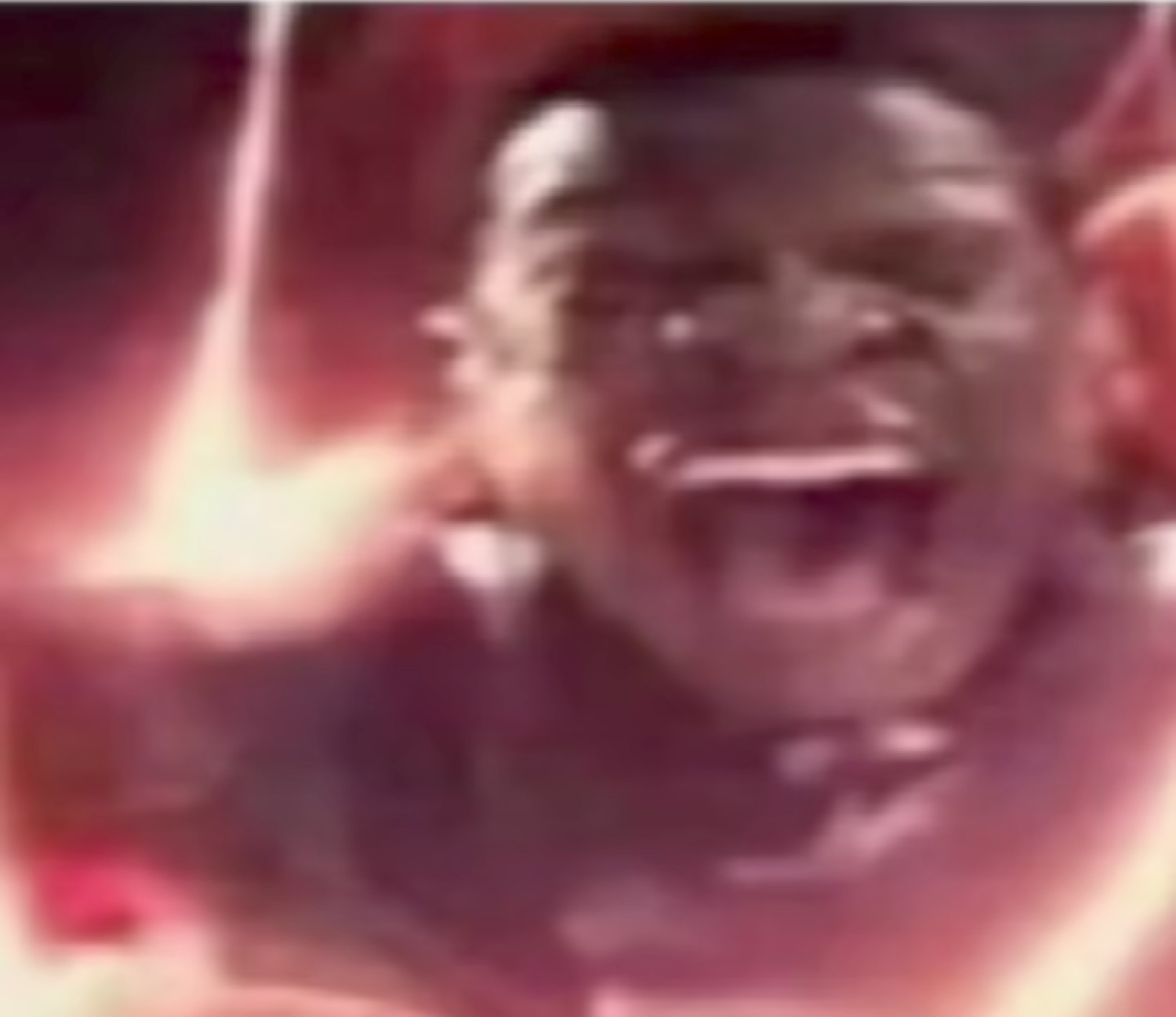 Man laughing uncontrollably with eyes squeezed shut amid a bright dramatic glow